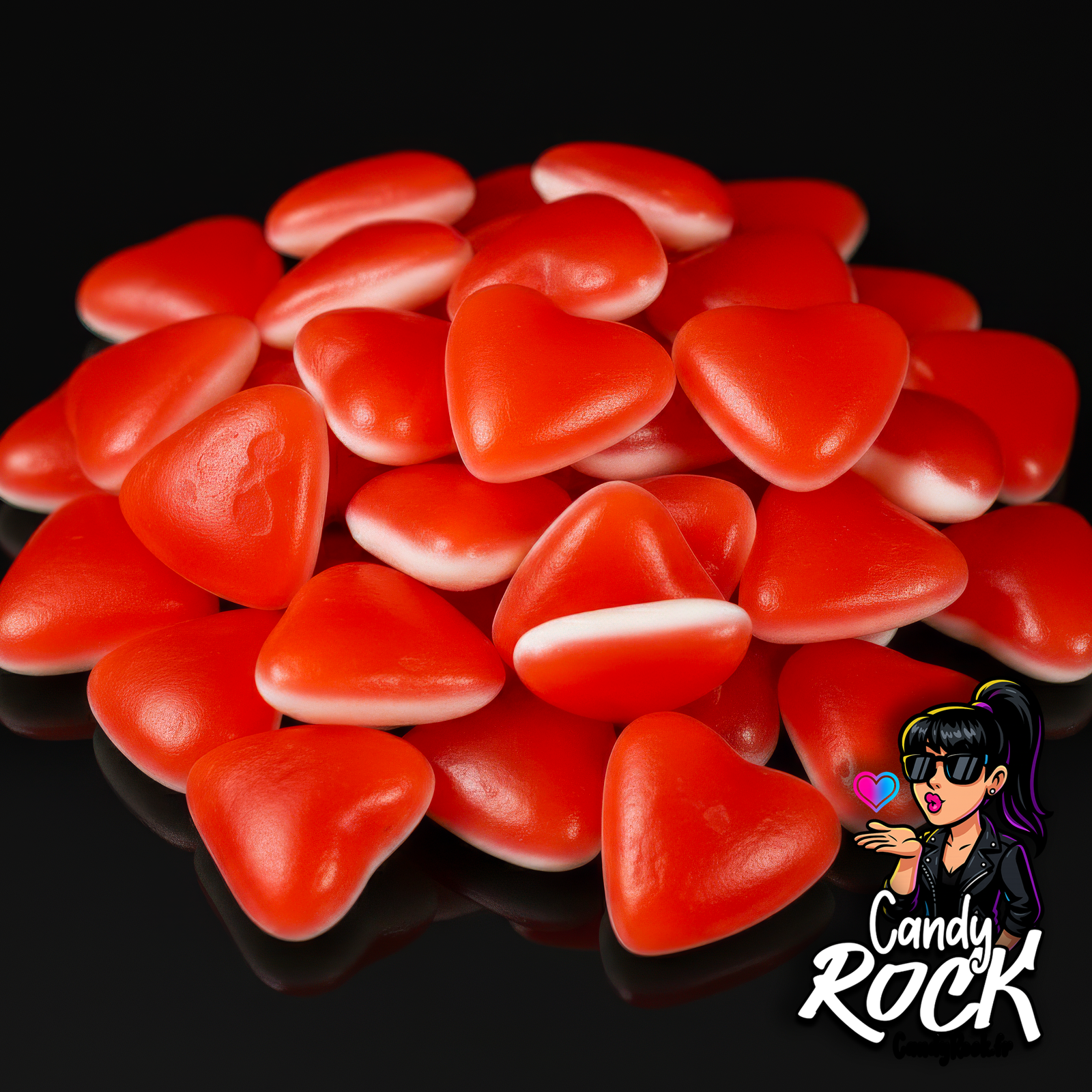 Cœurs gélifiés fraise crème lissés Dulceplus en tas, rouge brillant et blanc doux, sur fond noir CandyRock.