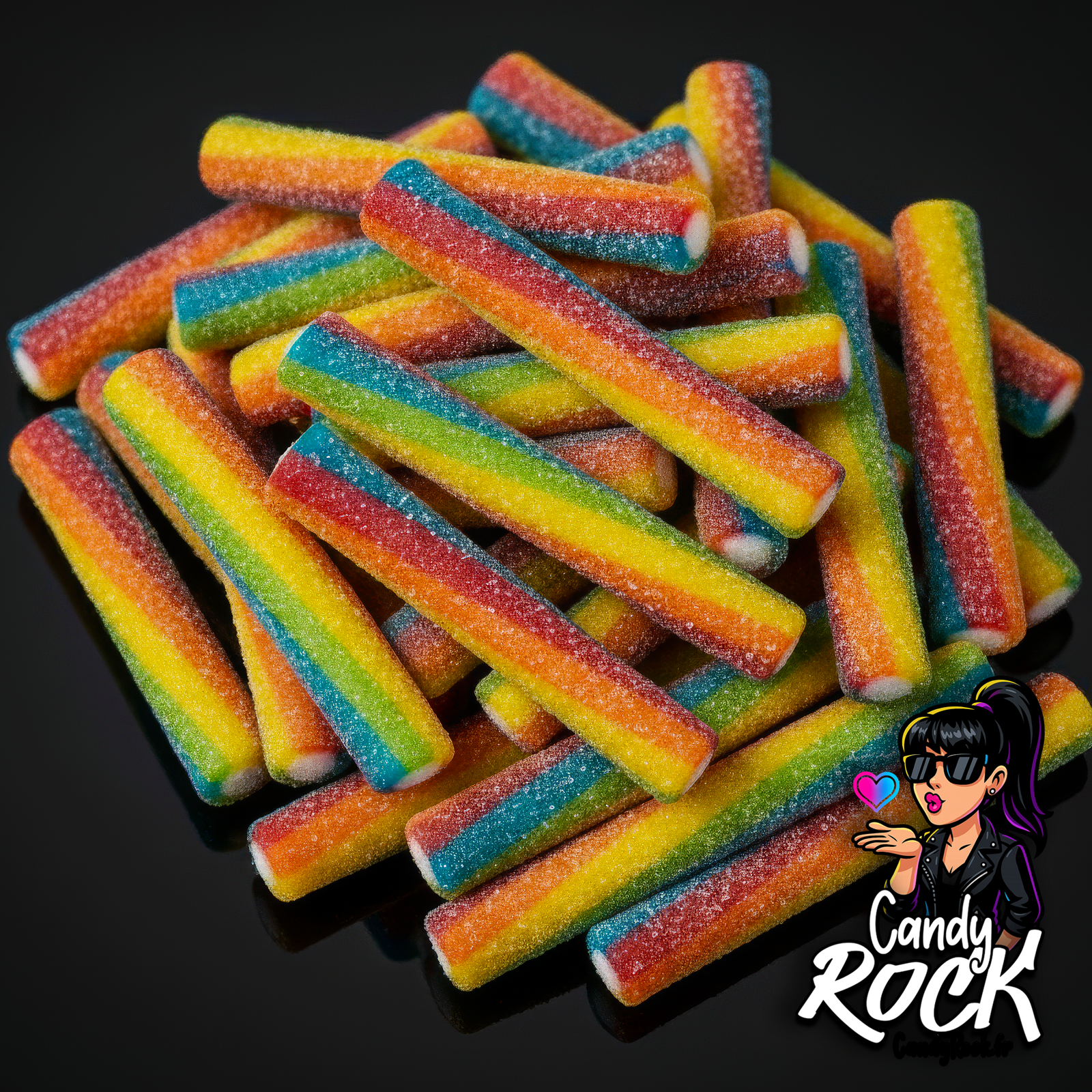 Jumbo sticks arc-en-ciel gélifiés avec sucre acidulé, présentés en vrac sur fond noir, CandyRock.
