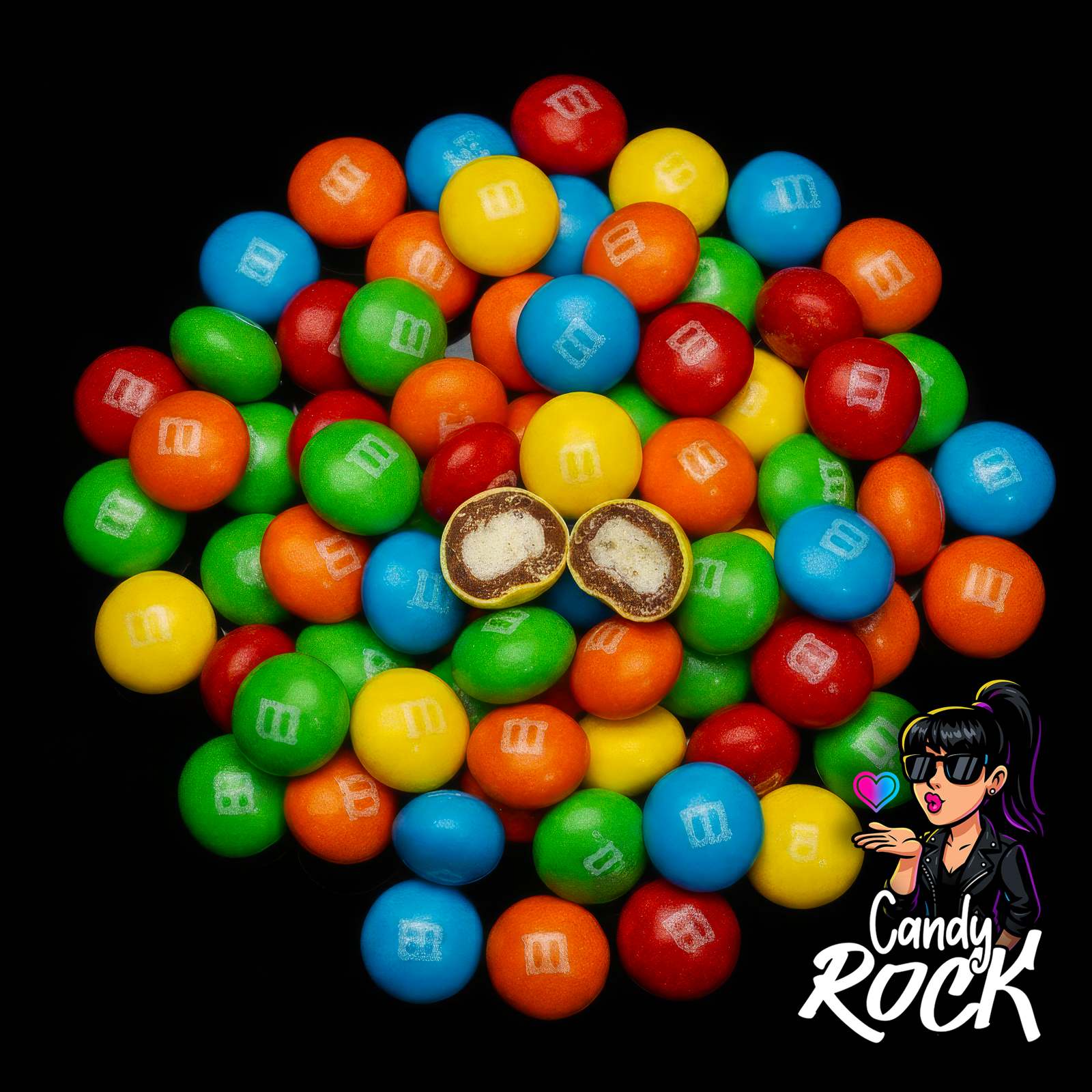 Tas de M&M’s Crispy brillants et multicolores sur fond noir avec deux dragées coupées révélant le cœur soufflé, CandyRock.