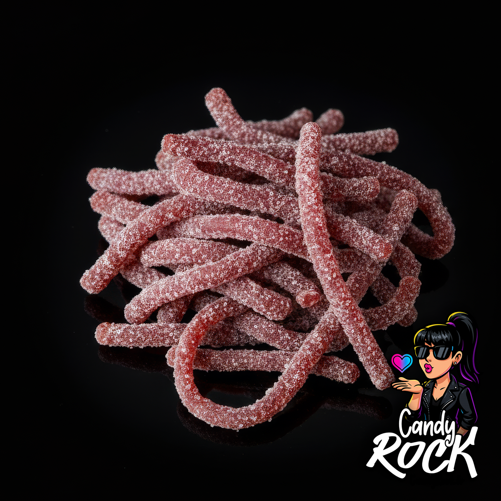 Gros plan sur des spaghetti cola acidulés, texture souple et sucre visible sur fond noir, CandyRock.